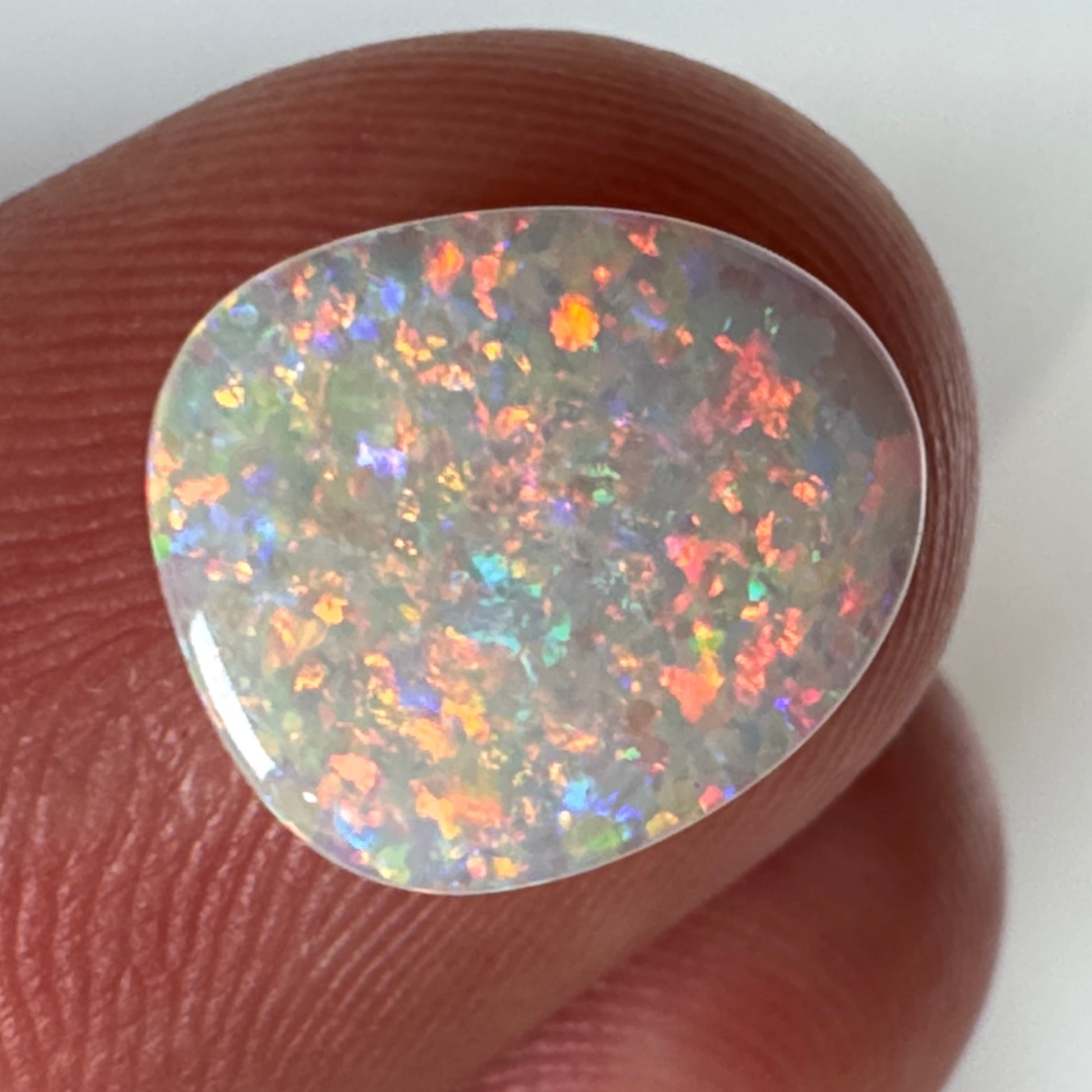 Opal stone held between fingers against a white background