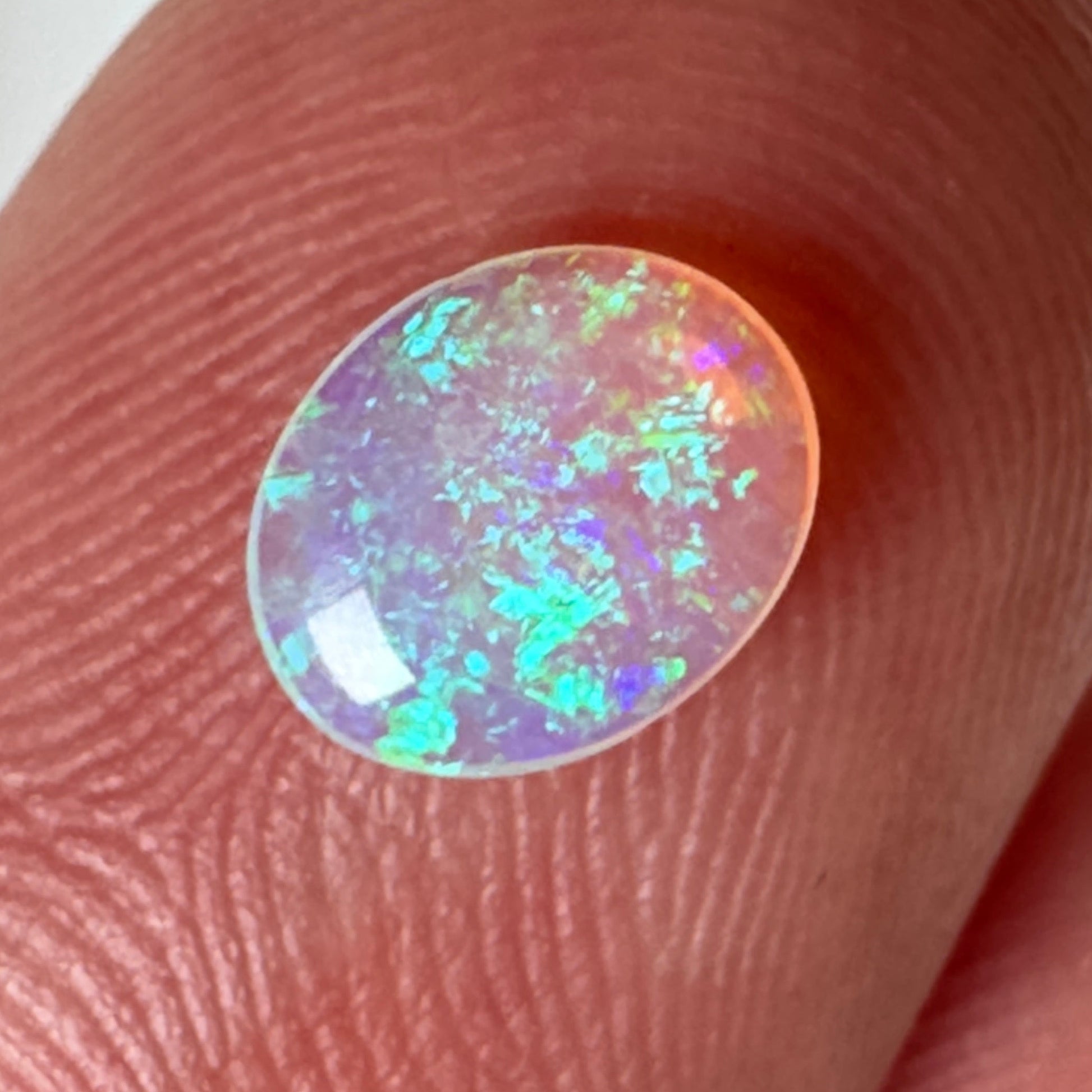 Opal stone held between fingers against a neutral background