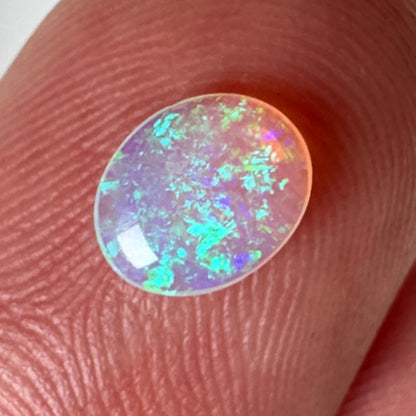 Opal stone held between fingers against a neutral background