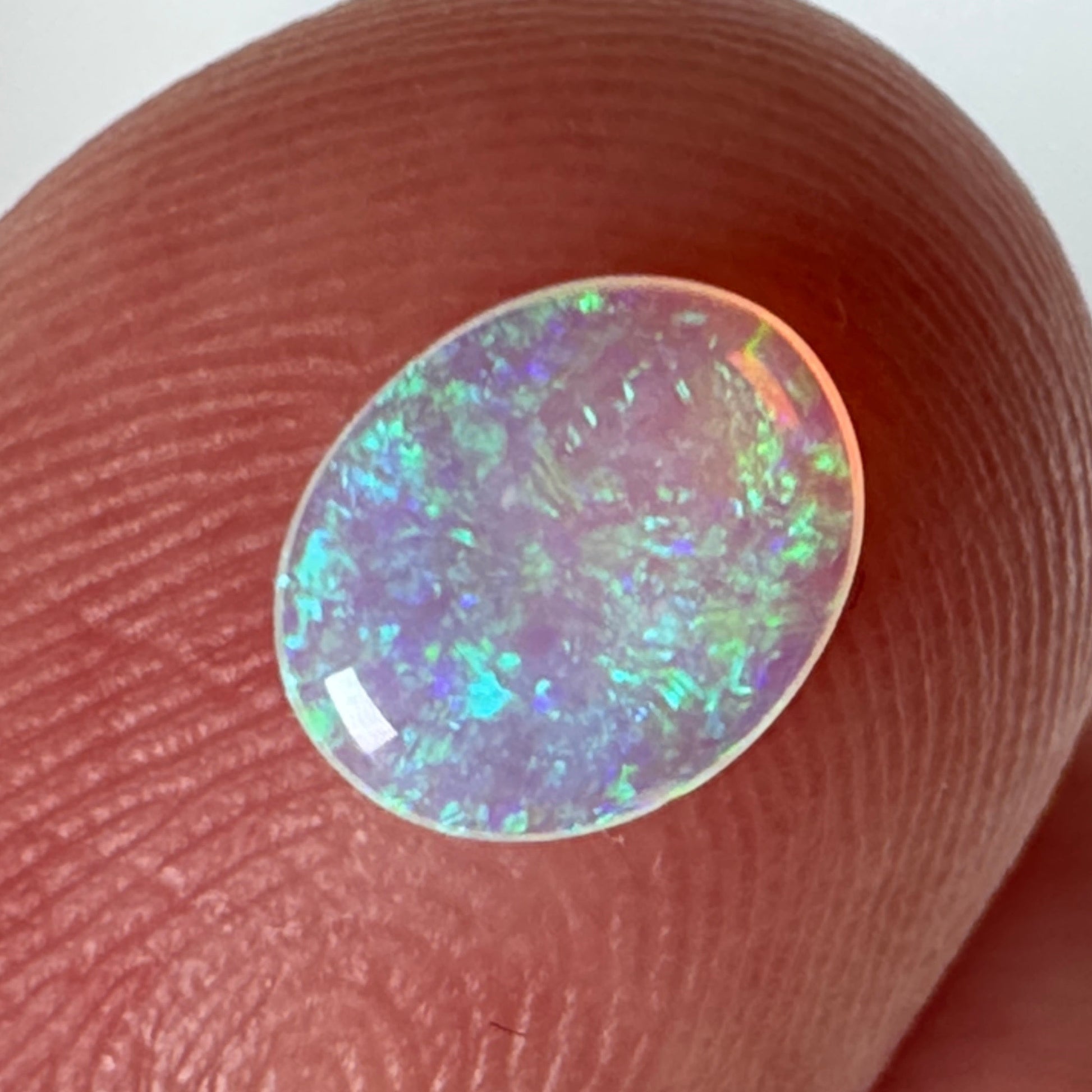 Opal stone held between fingers on a white background