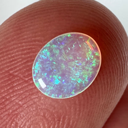 Opal stone held between fingers on a white background