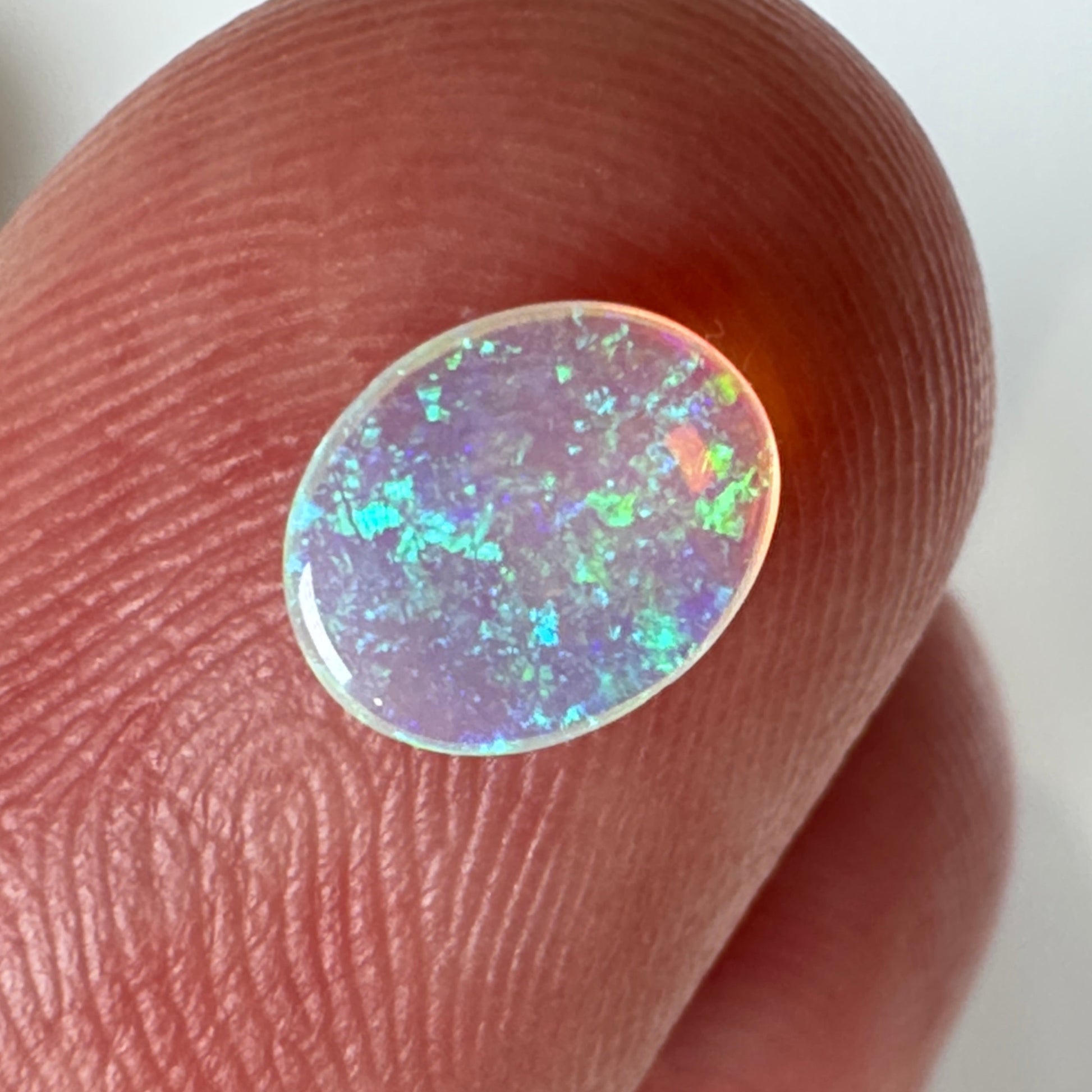 Opal stone held between fingers against a neutral background