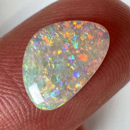 Opal stone held between fingers against a white background
