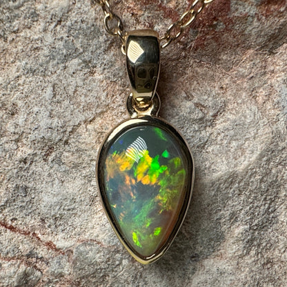 Opal pendant on a chain against a stone background
