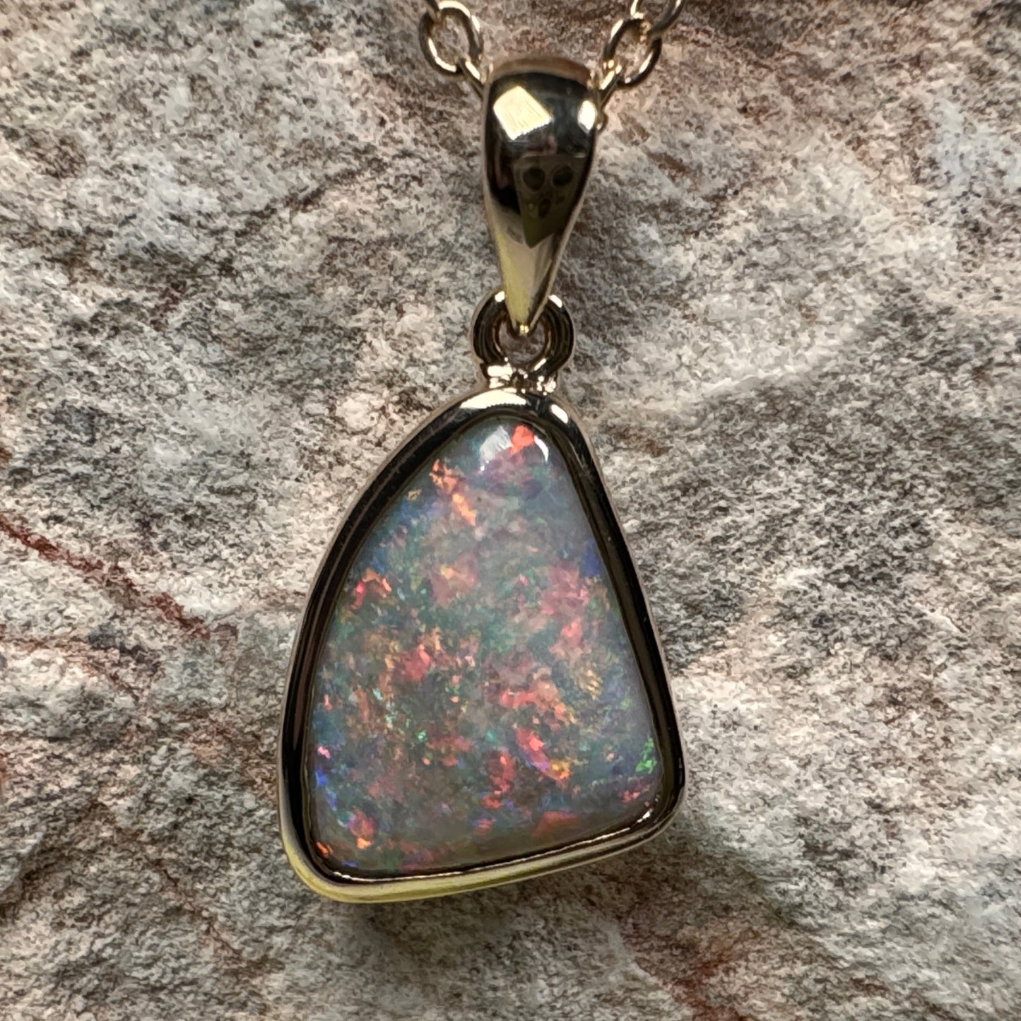 Opal pendant necklace on a textured stone background