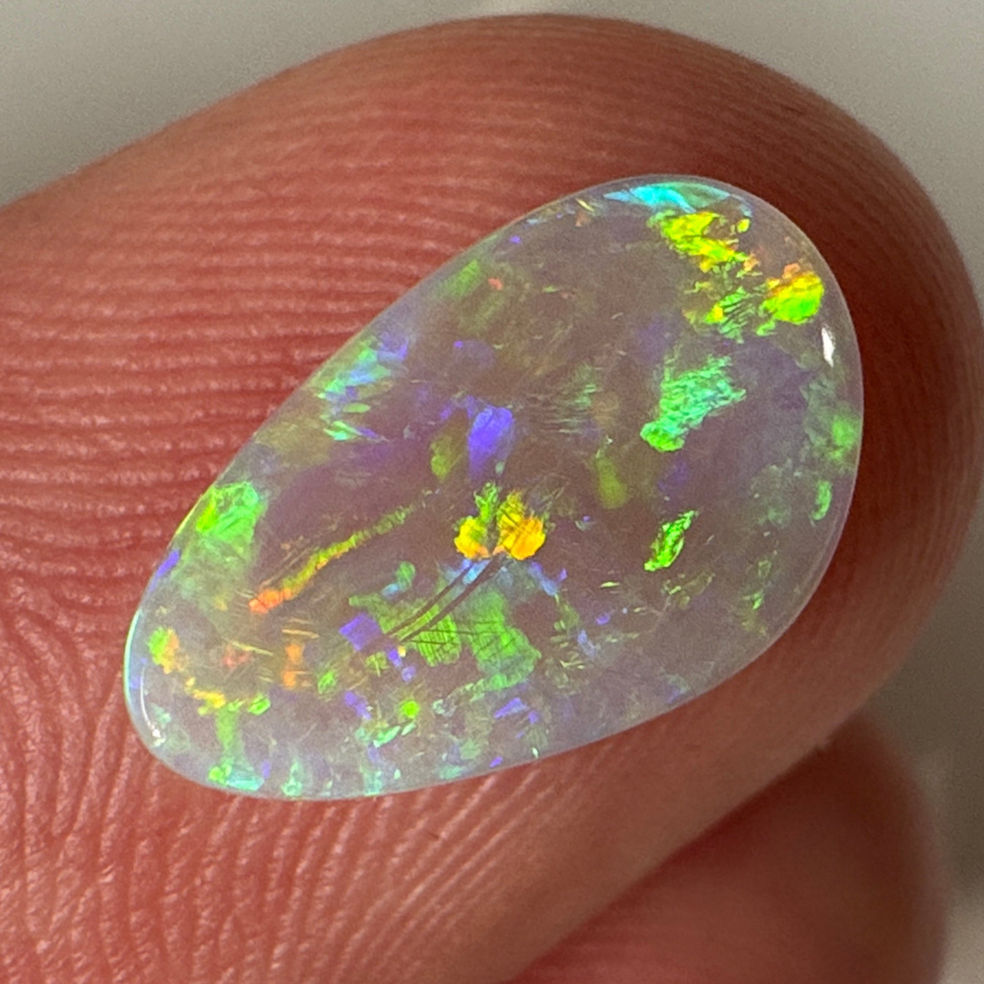 Opal stone held between fingers against a neutral background