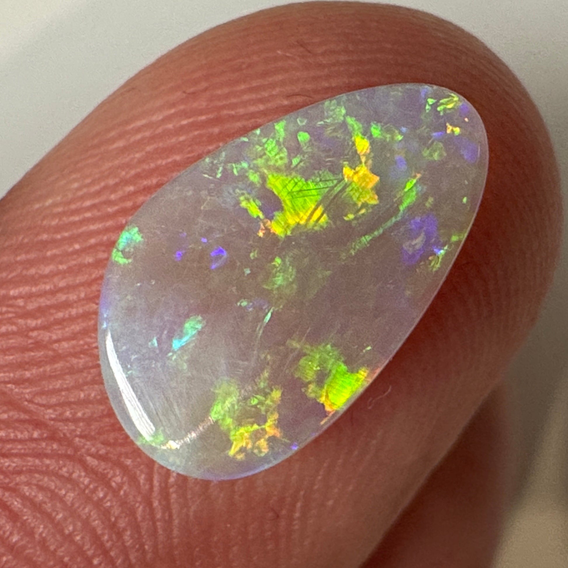 Opal stone held between fingers on a neutral background